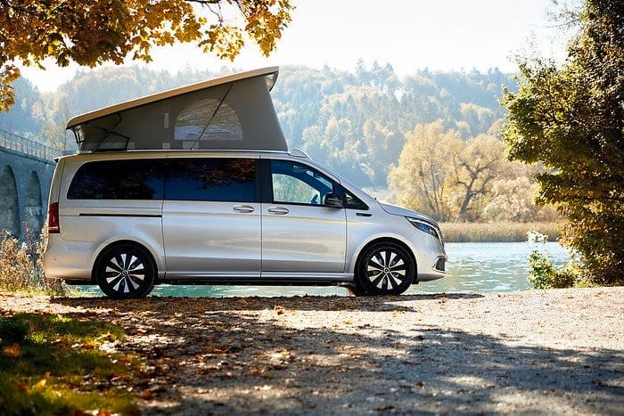 A high-end Mercedes-Benz camper van parked next to a lake.