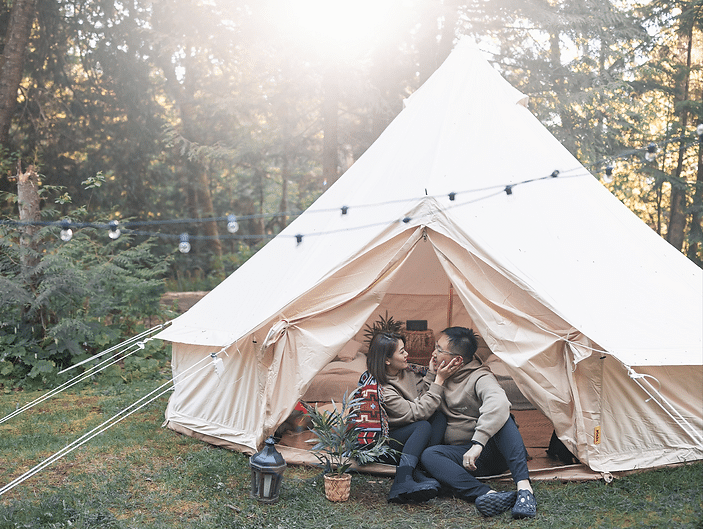 Two people sitting in front of a luxury tent in the woods near Metro Vancouver.