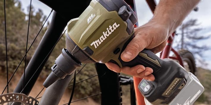 A person is using a Makita drill to fix a bicycle tire.