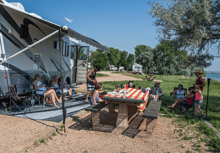 A group of people gathered around a picnic table at a Colorado Parks and Wildlife campsite.