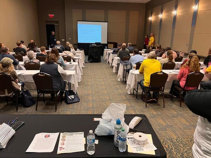 A group of people attending educational sessions in a conference room.
