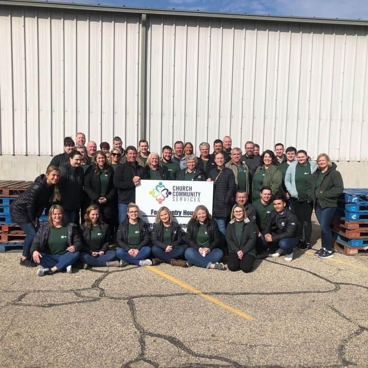 Partners of Elkhart Charity posing for a photo in front of a THOR Industries building.