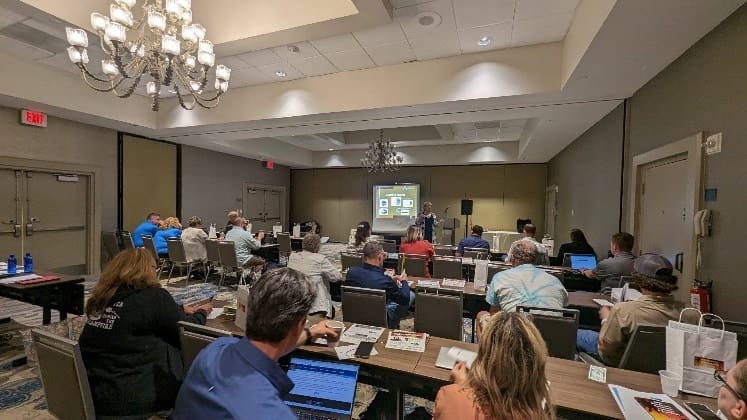 A group of people sitting at tables in a conference room expands the vendor list for the 2024 Mid-Atlantic Campground Conference.