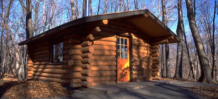 A small log cabin nestled in the serene Minnesota woods, located within a state park offering free entrance for visitors.