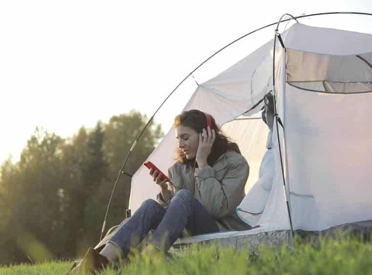 A woman sitting in a Modern Campground tent listening to music.