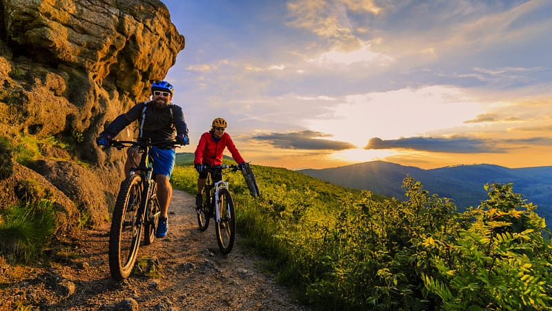 Two mountain bikers enjoying the outdoor recreation sector on a trail in Pennsylvania at sunset.