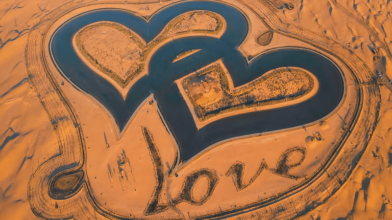 Two hearts shaped like a heart in the sand at Love Lake, Al Qudra's Romantic Getaway.