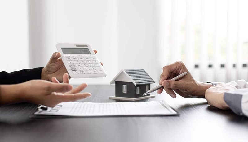 Two people holding a calculator and a house model for sale in Australia.