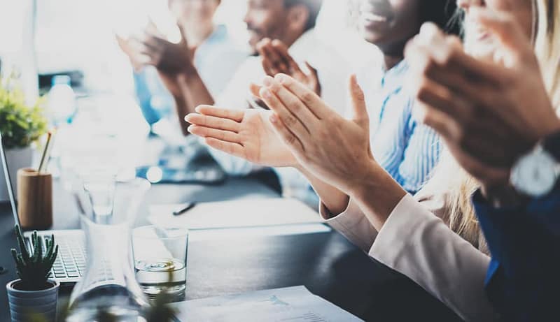 A group of people clapping at a Fastest-Growing Travel meeting.