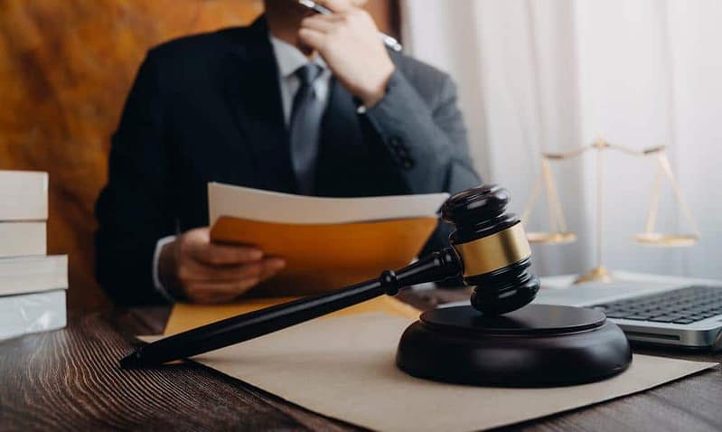 A man in a suit sitting at a desk with a gavel, discussing proposed legislation to protect Michigan campgrounds.