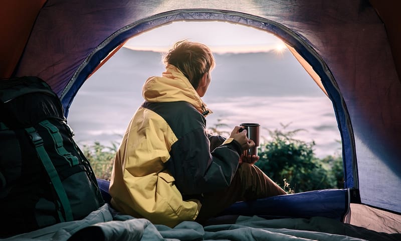 A woman sitting in a tent with a cup of coffee at Full Winter Occupancy in the Fraser Valley.