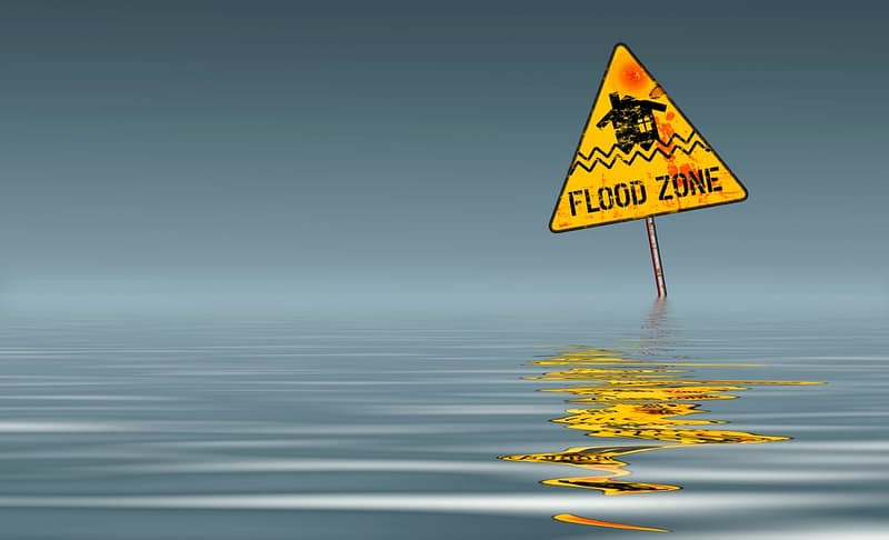 A yellow flood warning sign in the water.