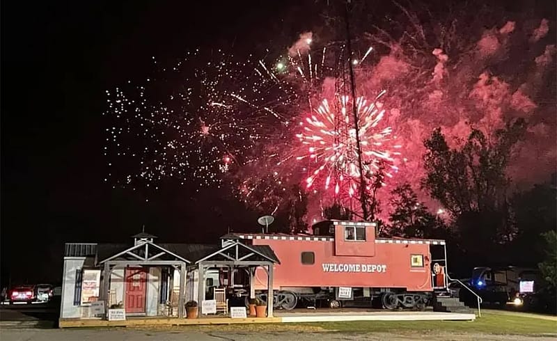 A vibrant firework display illuminates the sky in front of University Station RV Resort, creating a lively atmosphere for the hospitality community gathered together.