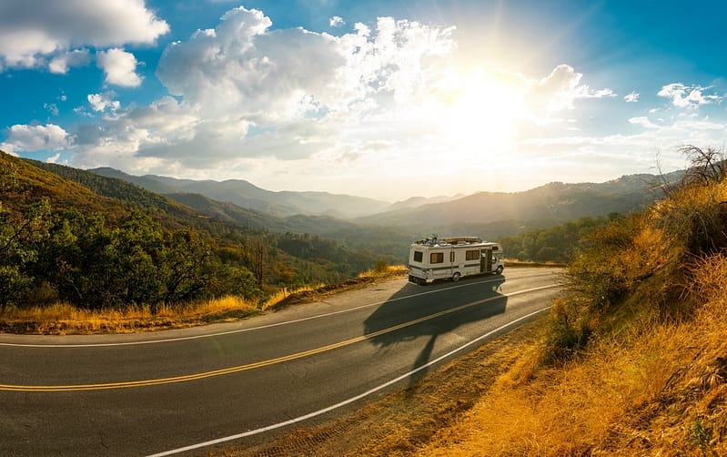 An rv traveling down a winding road in the mountains.