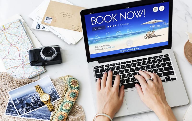 A woman is using a laptop to book a vacation on a camping reservations website.