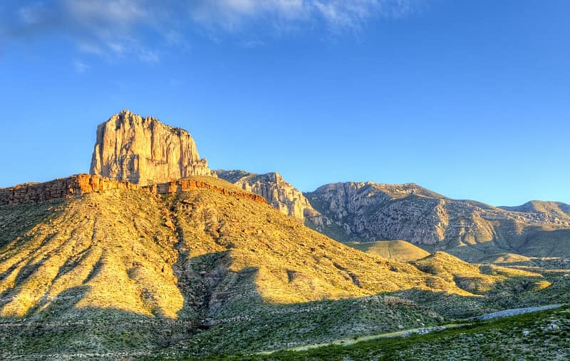 A mountain range with a large rock formation in the background located in Guadalupe Mountains National Park.