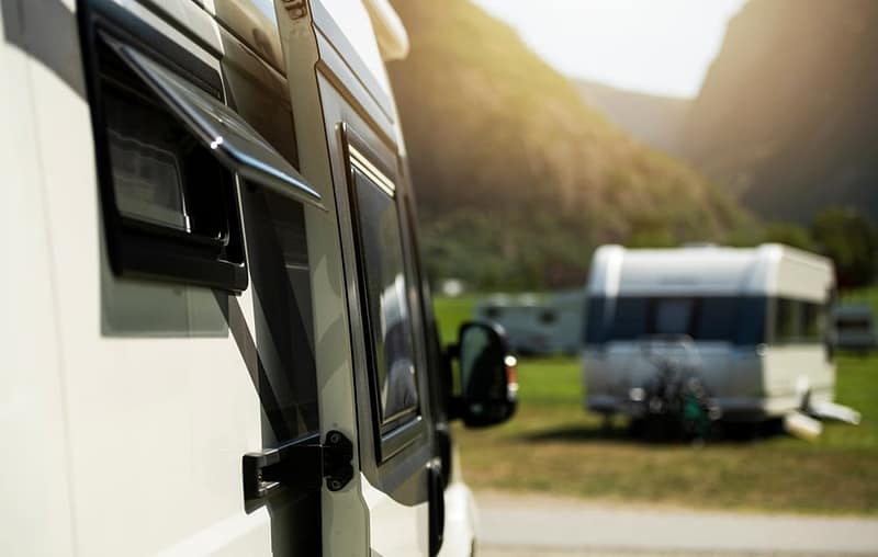 An rv parked in a field with mountains in the background at an Alberta campground.