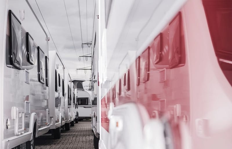 A row of RVs parked in a parking lot, showcasing the latest RV shipments for October.
