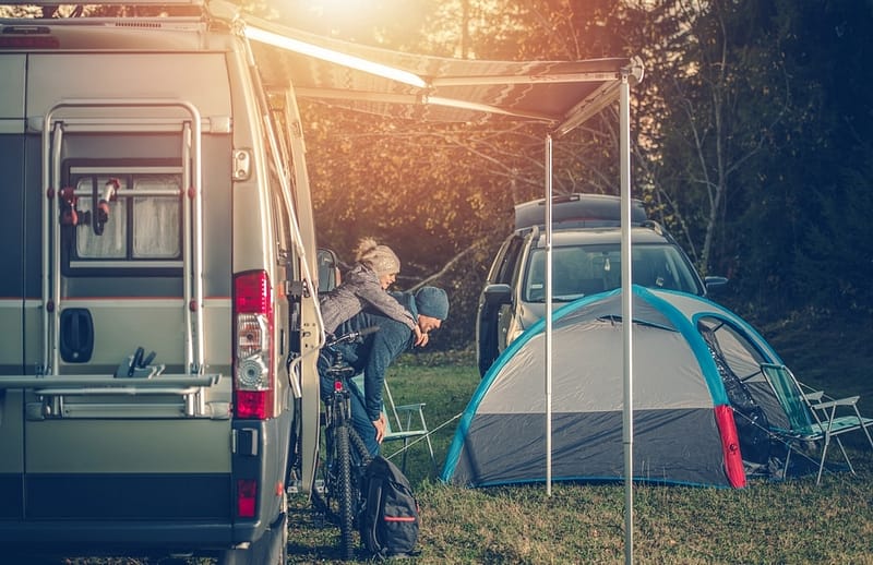 An outdoor recreation act showcasing the economic potential of the outdoor industry, featuring an RV with a tent and a man standing next to it.