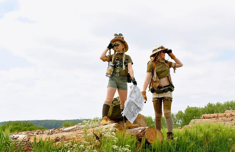 Two women in military uniforms standing on top of logs at the Get Out There Event.