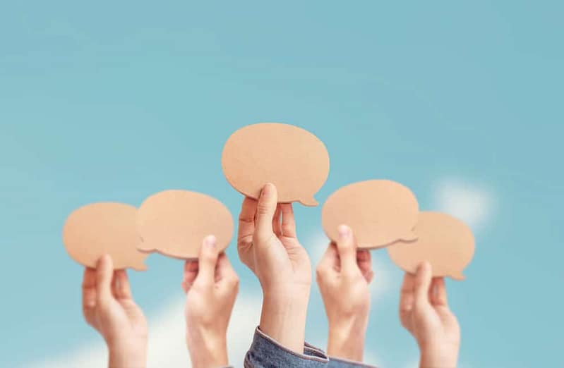 A group of hands holding paper speech bubbles discussing Land Management.