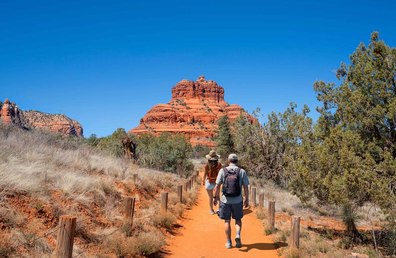 Two people walking down a trail in Sedona, Arizona, enjoying the scenic landscape.