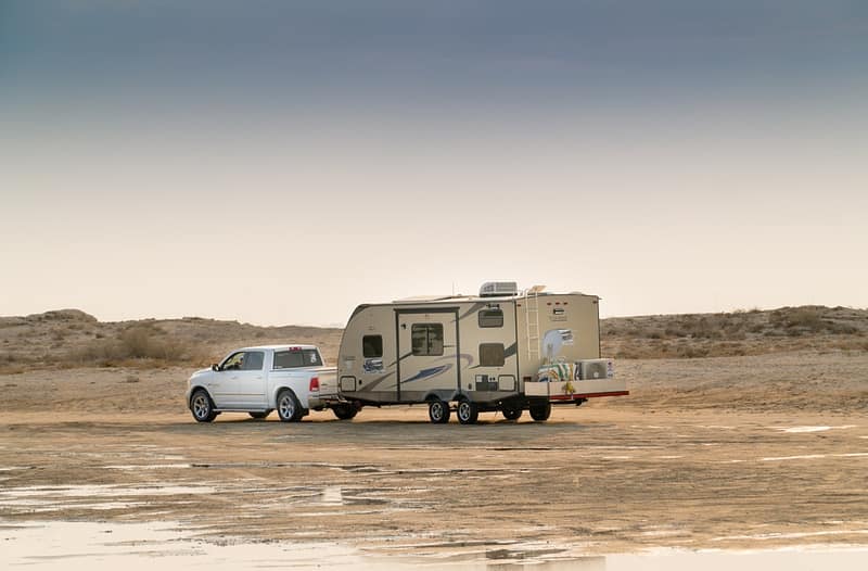 A white truck is parked next to a trailer.