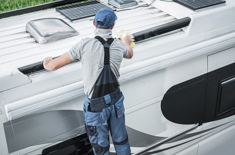 A man, trained in Premier Technician Training, diligently cleans the roof of an RV at the RV Technical Institute before October Awaits.