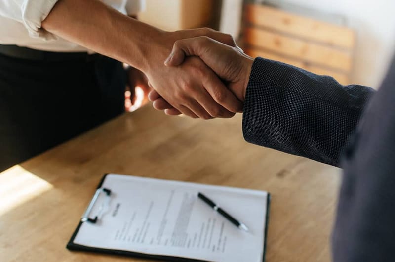 Two business people shaking hands over a document in Nahanni National Park Reserve.