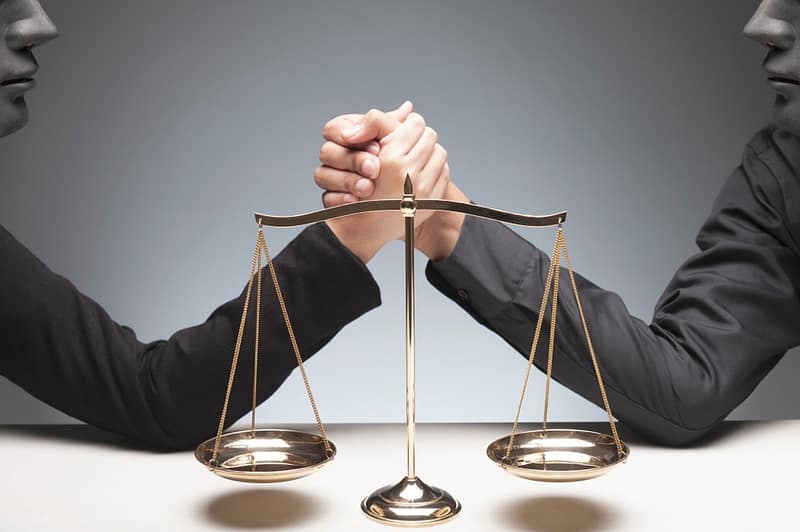Two business people engaged in a legal fight, holding scales of justice.