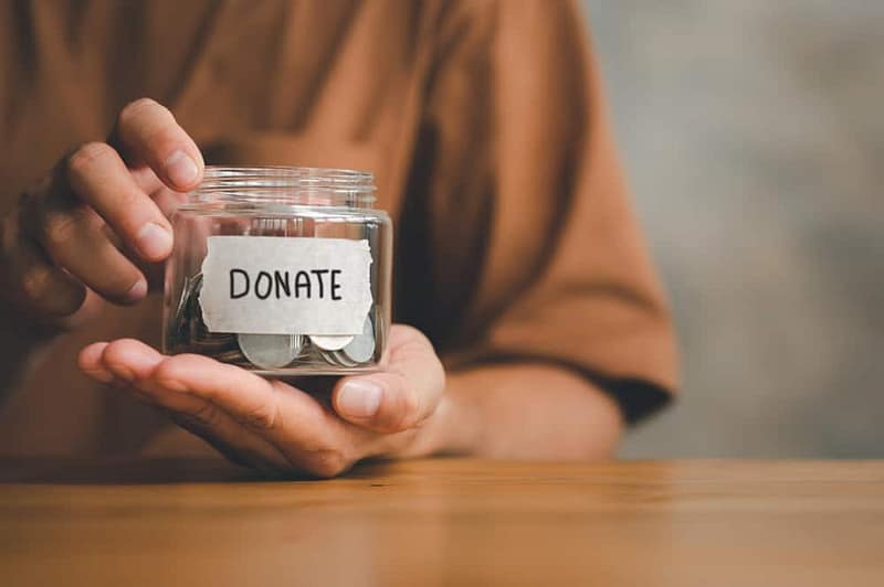 A man holding a jar with a note that says donate at a golf tournament.