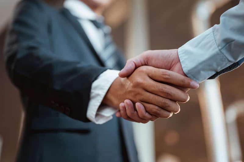 Two businessmen shaking hands in front of a building, signifying the new members joining the RV Industry Association.