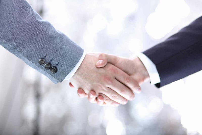Two businessmen shaking hands in front of a blurred background at Summerhill Resorts