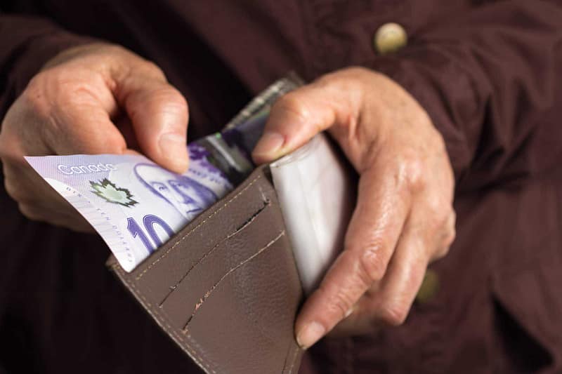 A woman is holding a wallet with money in it.