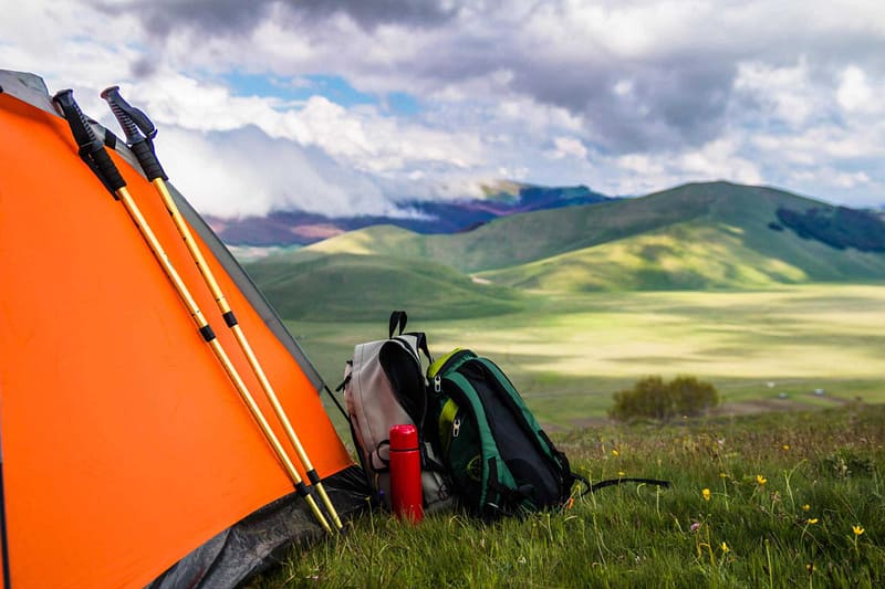 An outdoor recreation tent is set up in a grassy field, supported by a grant from Kootenay.
