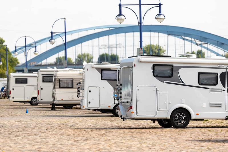 A group of German RVs parked in front of a bridge, showcasing the expansion and influence of the RV industry in Malaysia.