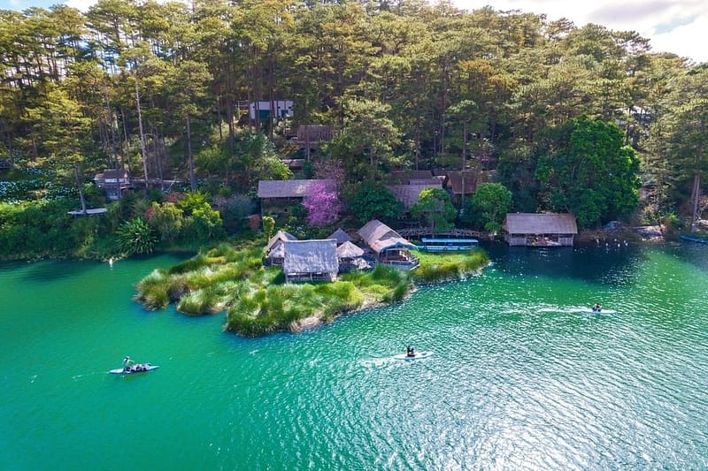 An aerial view of Tuyen Lam Lake with houses on it, a UNESCO-Recognized site in Vietnam.