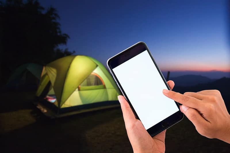 An exclusive night launch captured with a person holding a cell phone in front of a tent during CampLife.