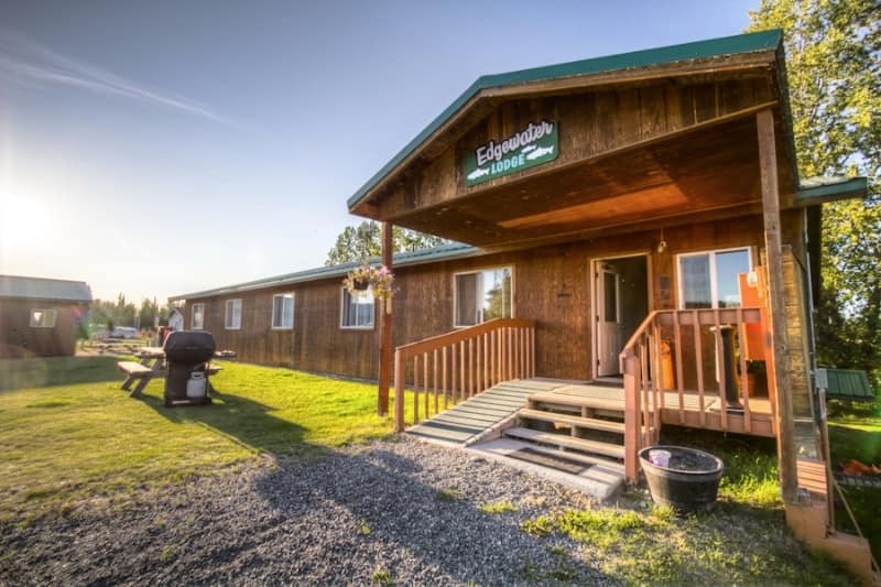 A cabin with a wooden deck and a bbq at Alaska’s Edgewater RV Resort.