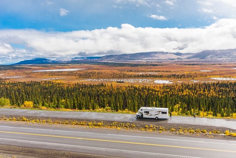 A roadtripper's rv exceeding speeds on a highway during the fall season.
