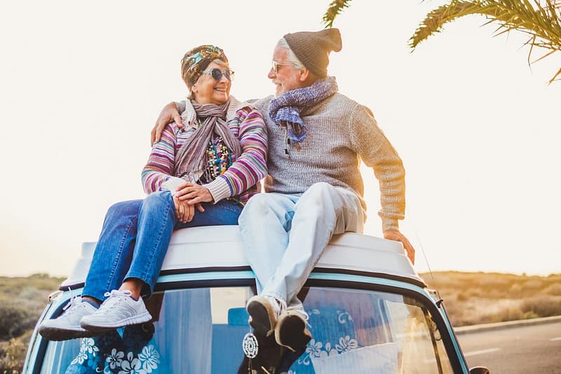 Elderly snowbirds sitting on top of a van at sunset.