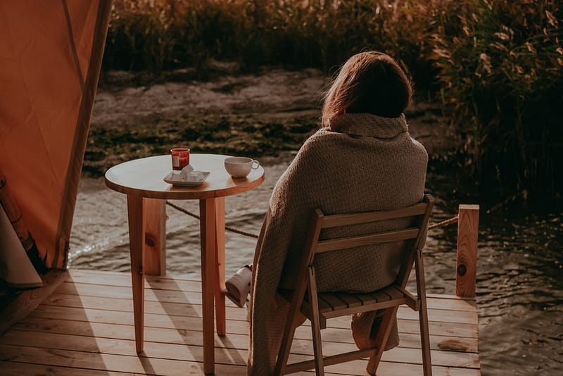 A woman sitting on a chair in front of a glamping pod in Derbyshire Village.