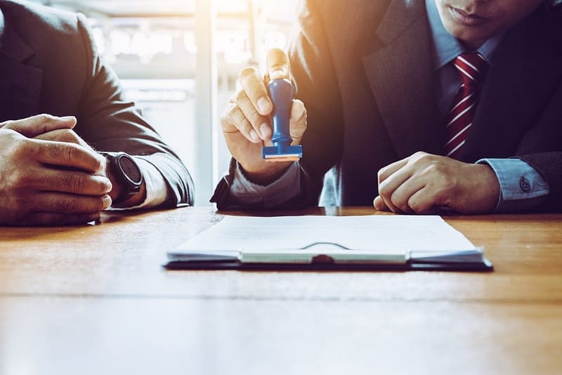 Two businessmen signing a document at a table.
