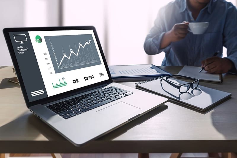 A man is sitting at a desk with a laptop displaying Q3 2021 financial results.