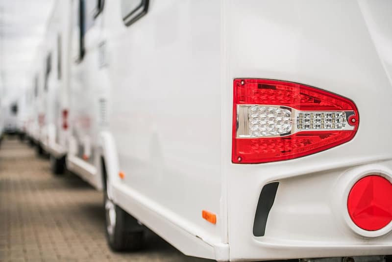 A row of Apache and Nucamp white RVs parked in Tom's Camperland parking lot.