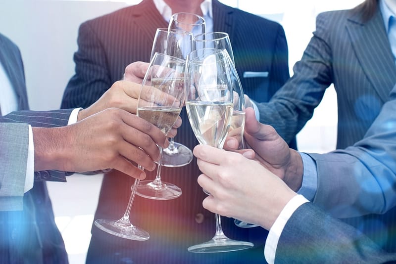 RVReviews.net celebrates 20 years with a group of business people toasting champagne glasses.