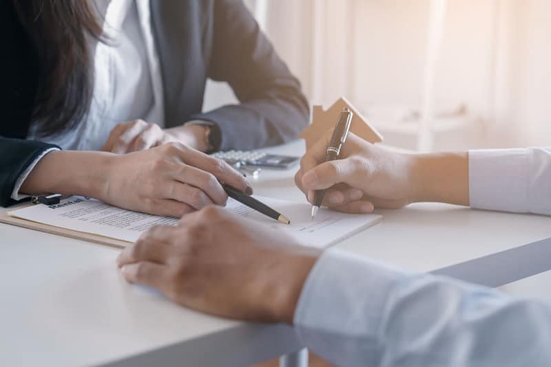 Two people signing a document at a desk in a warehouse.