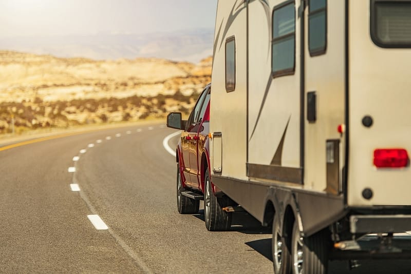 In the Year of the RV 2021, an RVIA-certified rv is zooming down the road with a vibrant red truck tailing closely behind.