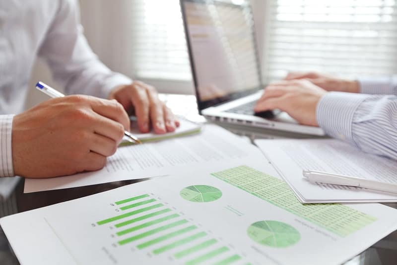 Two businessmen working on paperwork for the sustainability report at a desk.