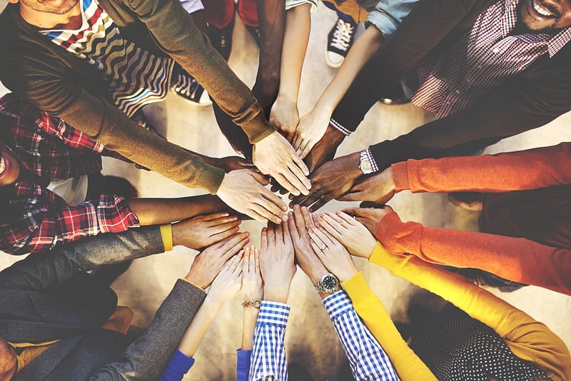 A team of people putting their hands together in a circle.